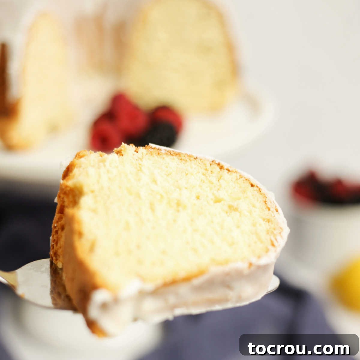 Sun-Kissed Lemon Bundt with Ginger Drizzle 9 A slice of lemon Bundt cake being lifted from a serving plate, ready to be enjoyed.