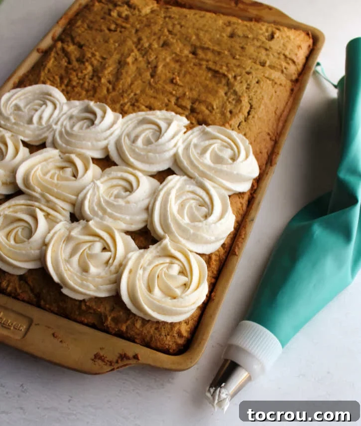 Decorating Pumpkin Spice Cookie Bars A baking tray filled with pumpkin spice bars, with a piping bag adding buttercream rosettes on top.