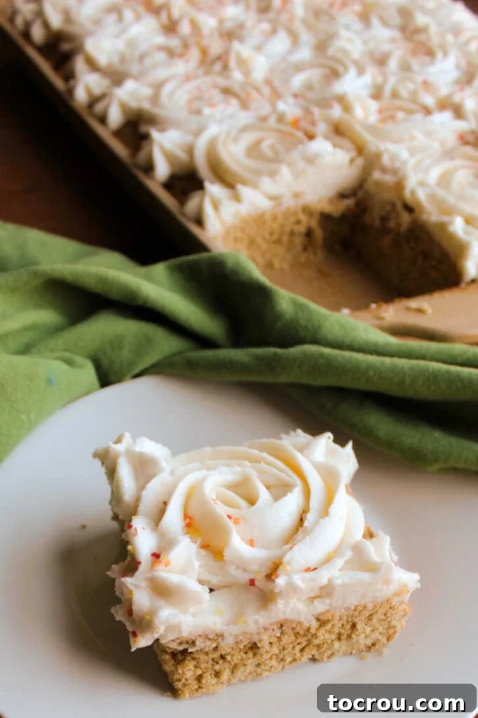 Pumpkin Spice Cookie Bar on a Plate A perfectly sliced pumpkin cookie bar presented on a white plate, with the rest of the pan visible in the soft-focus background.