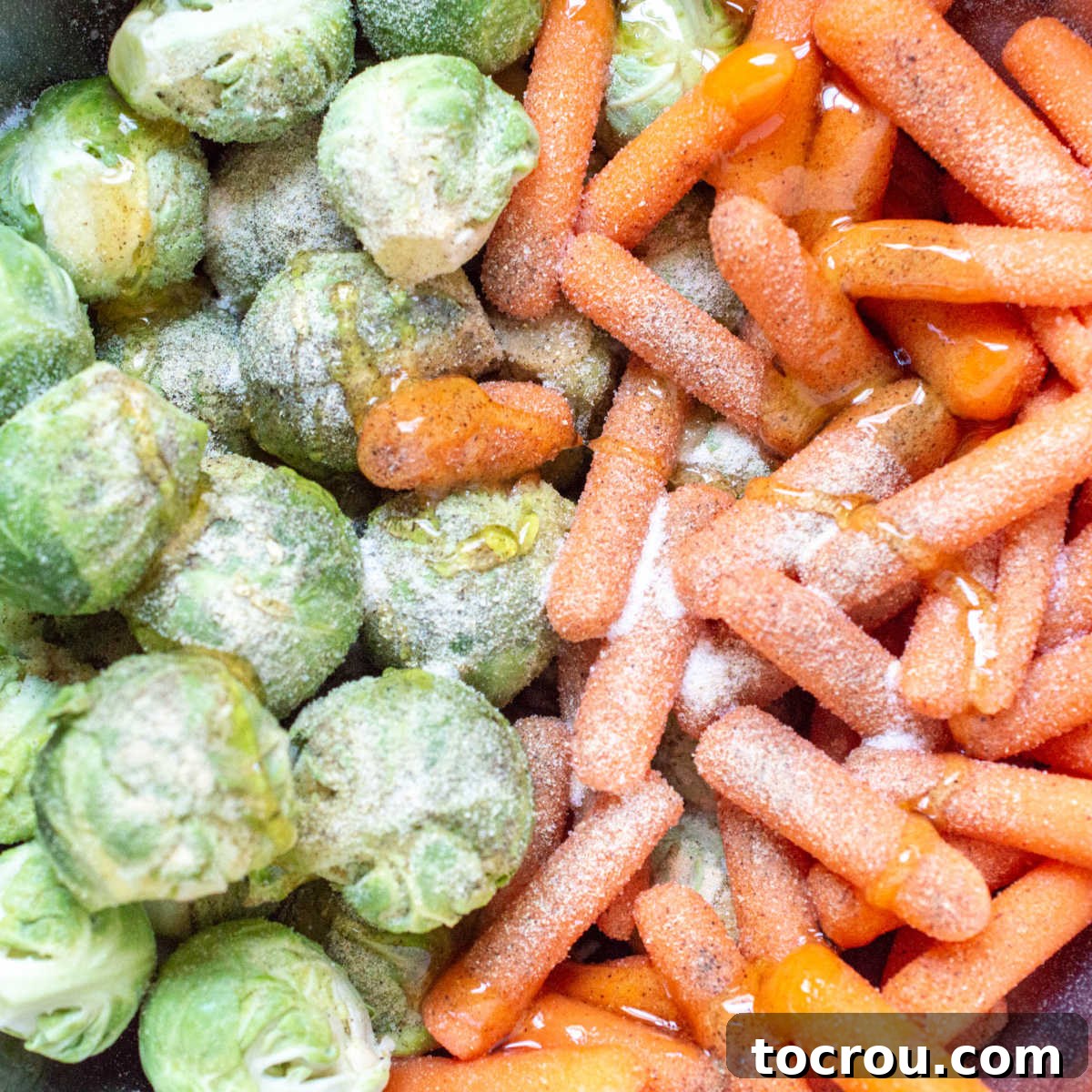 Seasoned Vegetables Ready for Roasting Brussels sprouts and carrots generously seasoned with salt, pepper, garlic, and glistening with honey before roasting.