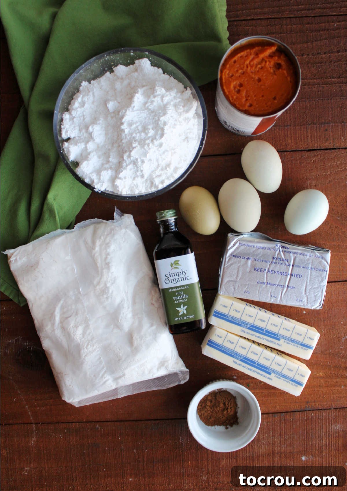 Ooey Gooey Pumpkin Butter Cake 3 Arrangement of key ingredients for Pumpkin Gooey Butter Bars: yellow cake mix, eggs, butter, cream cheese, vanilla extract, pumpkin puree, powdered sugar, ground cinnamon, and grated nutmeg.