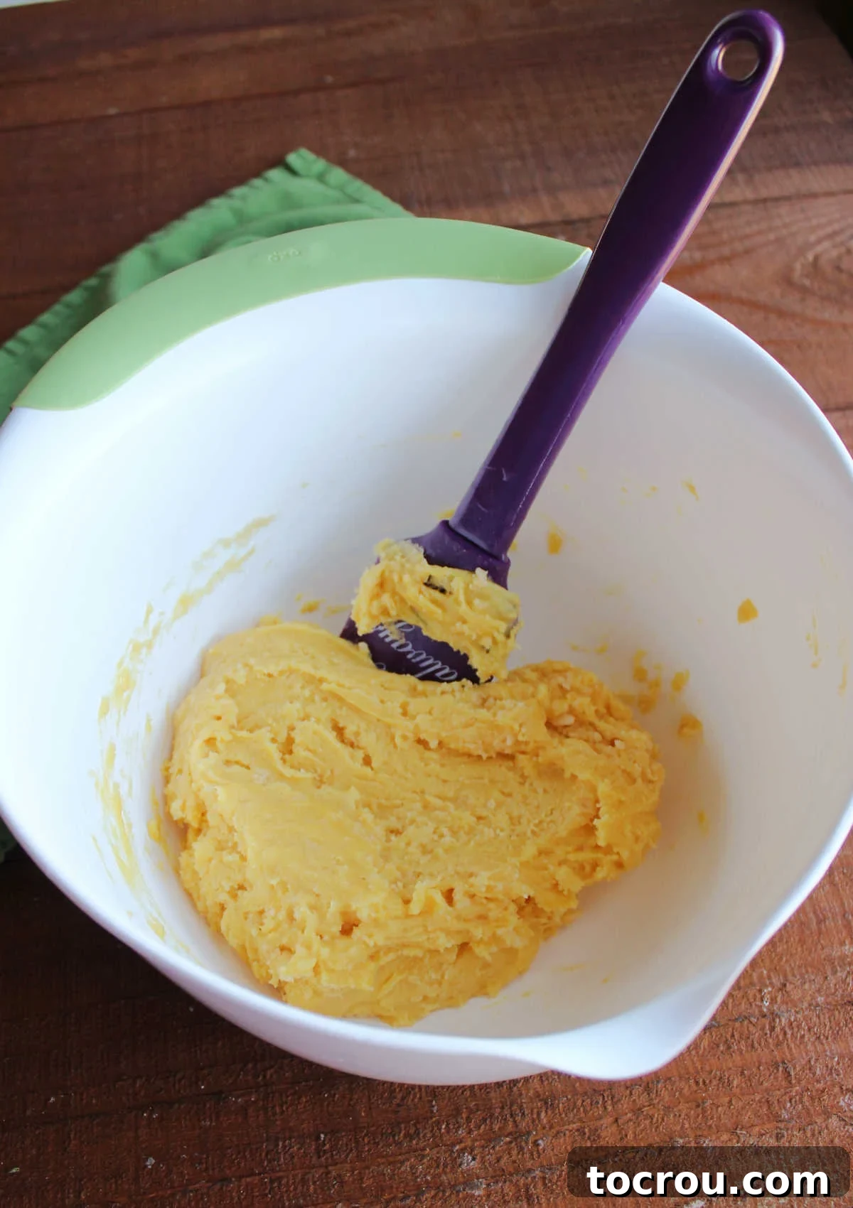 Ooey Gooey Pumpkin Butter Cake 5 A mixing bowl filled with a thick, golden mixture of cake mix, melted butter, and egg, forming the rich base for the gooey butter cake crust.