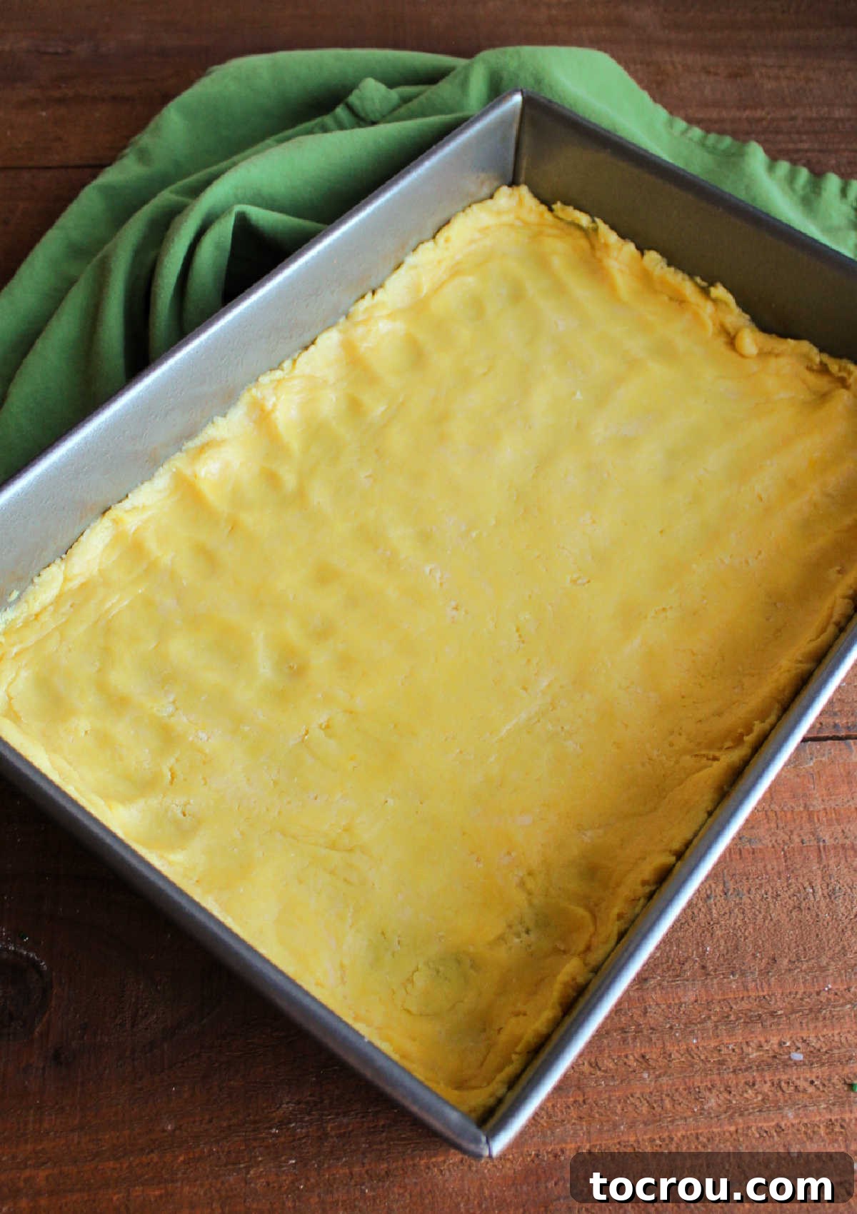 Ooey Gooey Pumpkin Butter Cake 6 The dense cake mix batter, combined with butter and egg, expertly pressed into the bottom of a 9x13-inch baking pan, creating a sturdy foundation for the dessert.