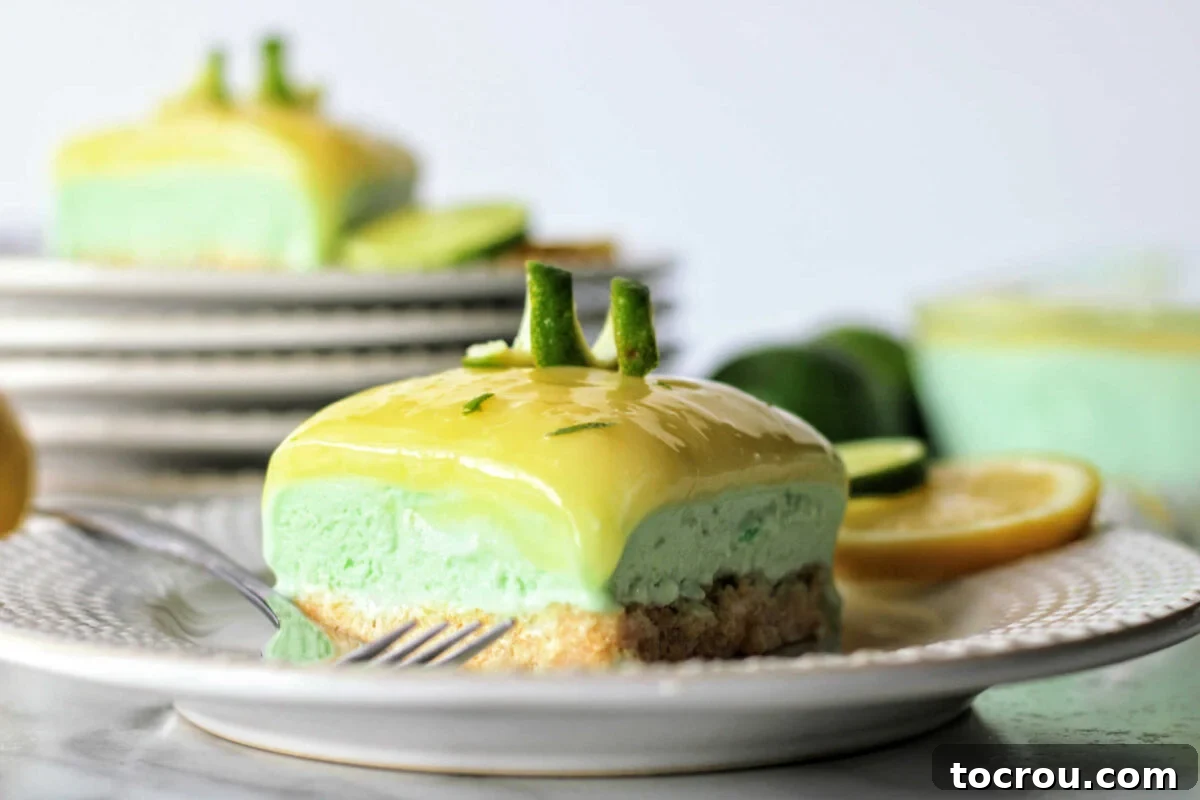 Lemon lime sherbet bar on plate showing crumb crust, pale green lime layer and yellow lemon curd on top with a lime peel spiral for garnish, ready to eat.