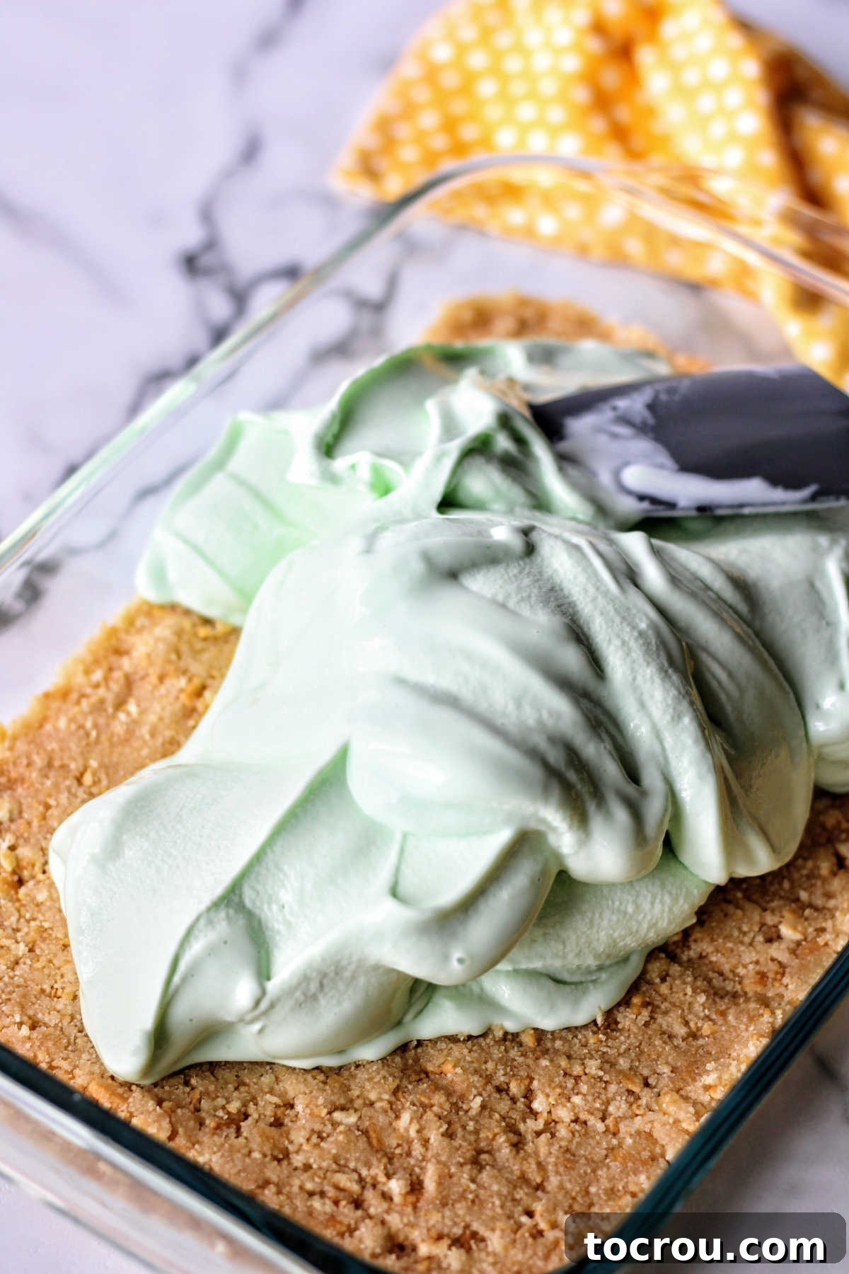 Spreading lime sherbet and ice cream mixture over cracker crust.