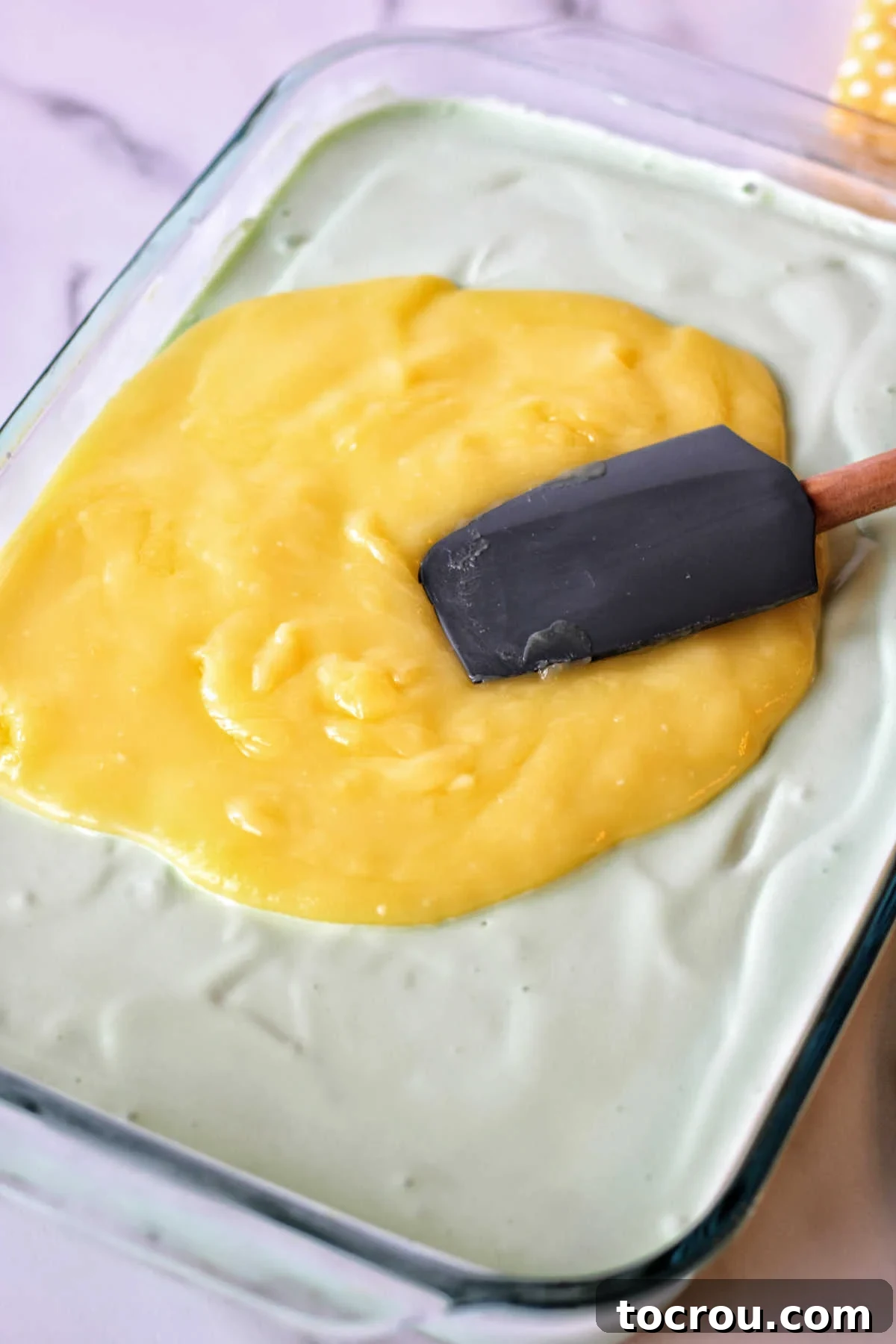 spreading lime curd over sherbet mixture in 9x13 pan.