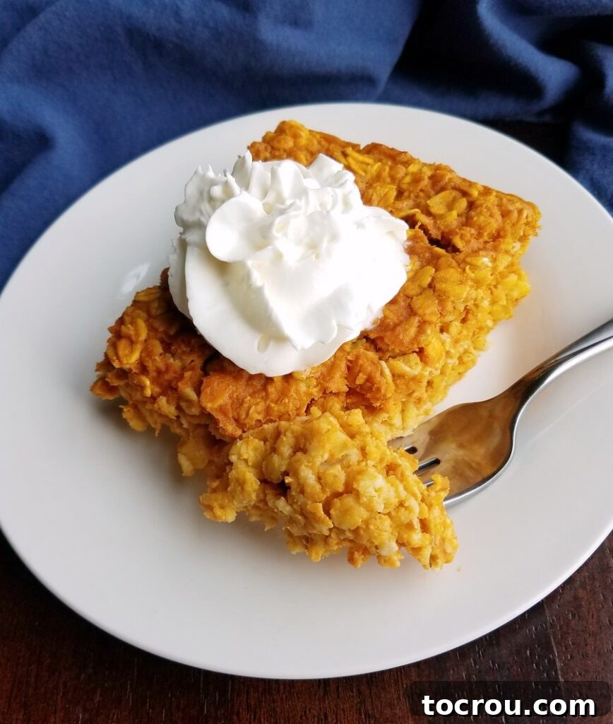 A beautifully presented piece of pumpkin baked oatmeal, elegantly topped with a swirl of airy whipped cream, suggesting a delightful and decadent breakfast treat.