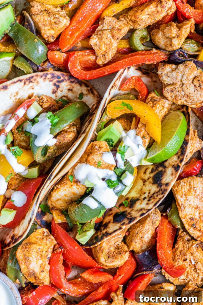 One-Pan Chicken Fajitas 7 sheet pan chicken fajitas in tortillas with sour cream, lime wedges and cilantro.