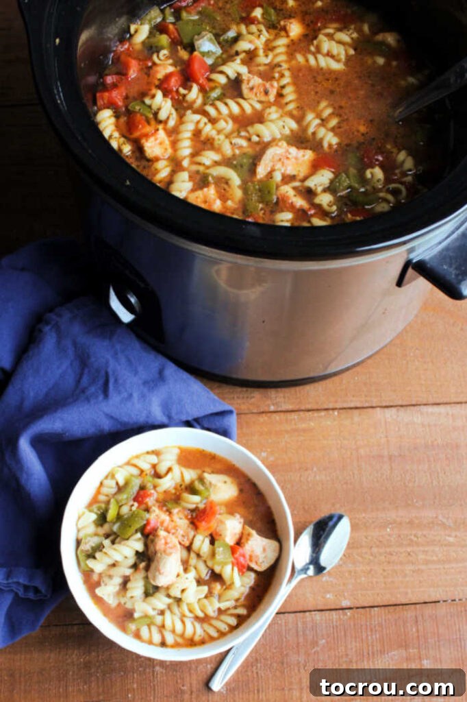 Italian Chicken Soup Served A bowl of Italian chicken pasta soup placed next to a slow cooker, emphasizing the ease of preparation and serving.