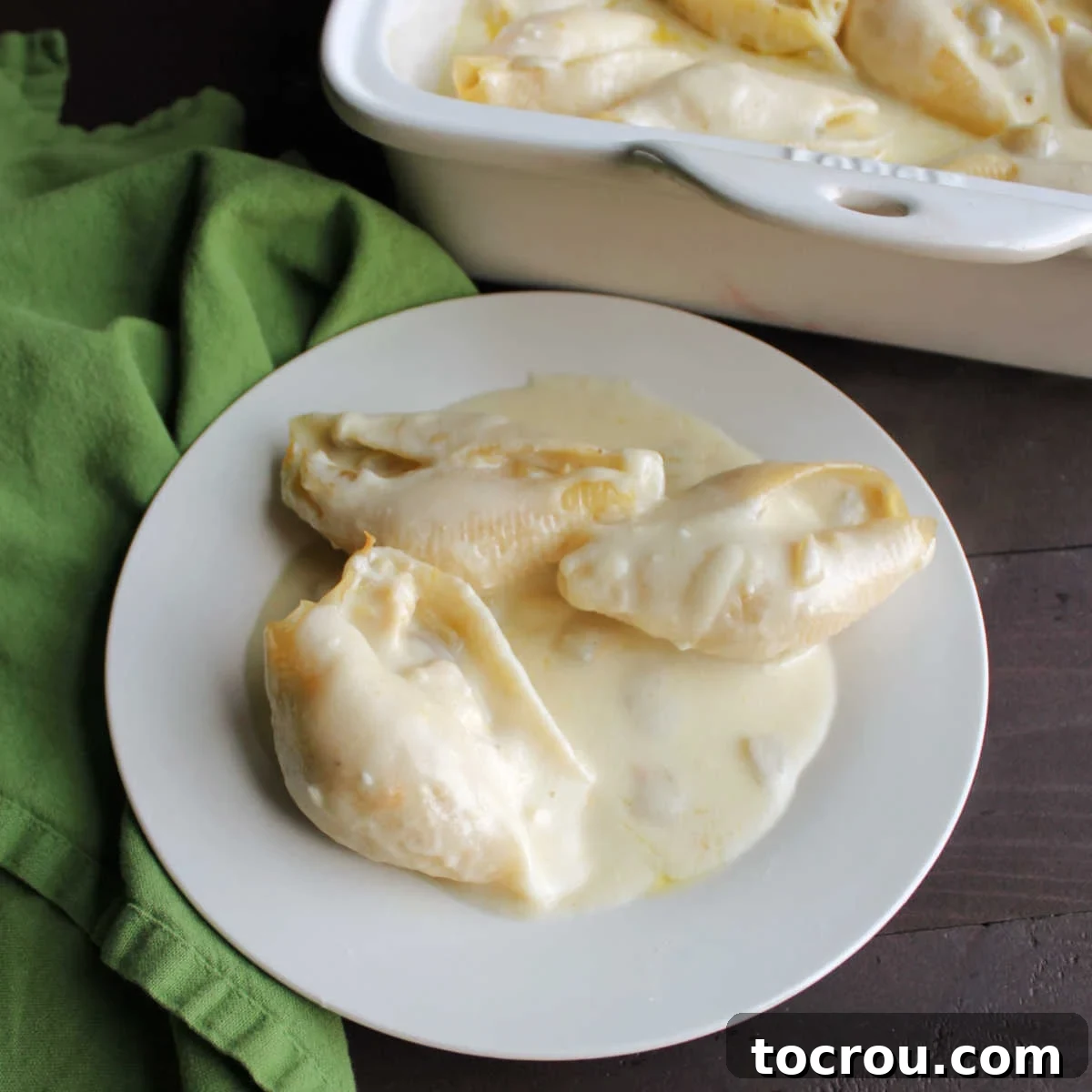 Cheesy chicken enchilada stuffed shells with a creamy sour cream and cheese sauce, garnished with fresh herbs.