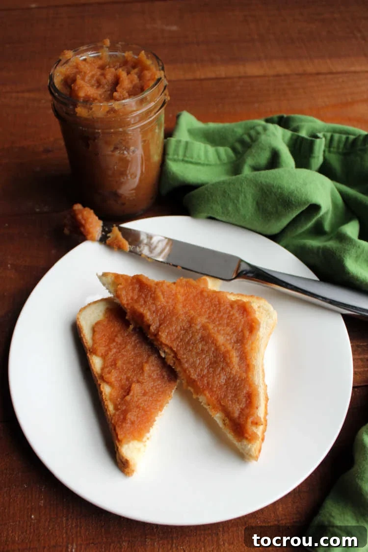 Homemade Apple Butter Ready for Toast jar of apple butter with knife and apple butter coated toast.