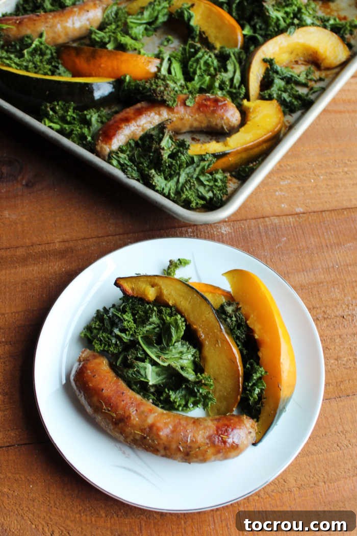 A vibrant plate featuring a harmonious mix of Italian sausage, roasted kale, and acorn squash, with the well-used sheet pan visible in the background, testament to a delicious meal cooked with ease.