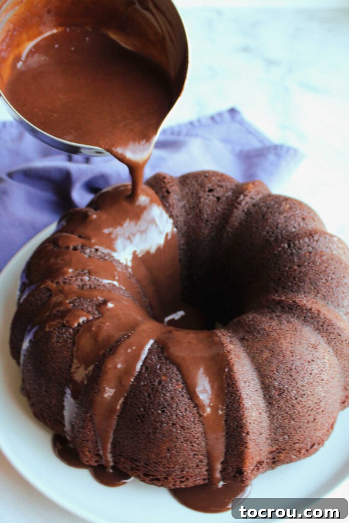 Pouring fudgy chocolate glaze over chocolate bundt cake.
