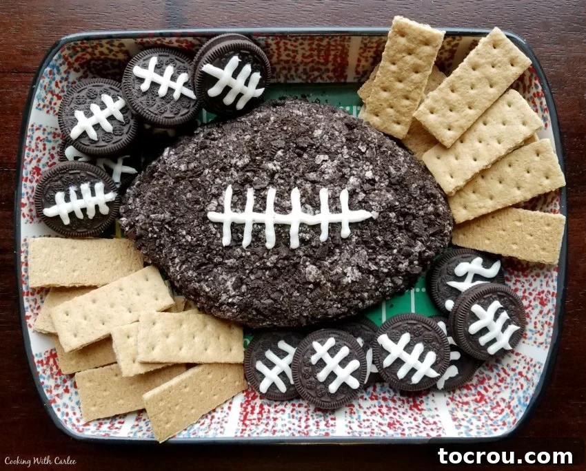 Chocolate football shaped cheese ball with cookies for dippers, ready for game day.