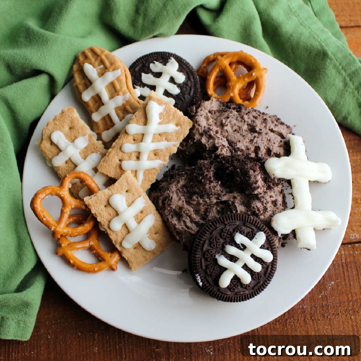 Plate of Oreo cheese ball with cookies decorated with football laces and graham crackers.