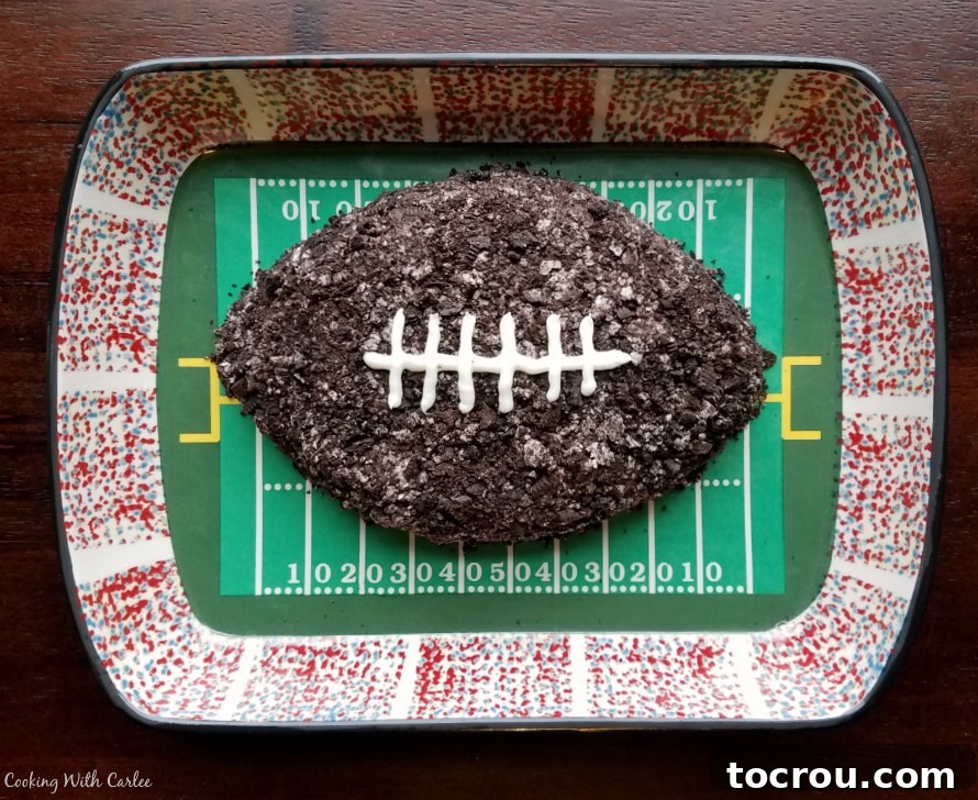Football shaped Oreo dessert dip in football themed serving dish with various dippers.