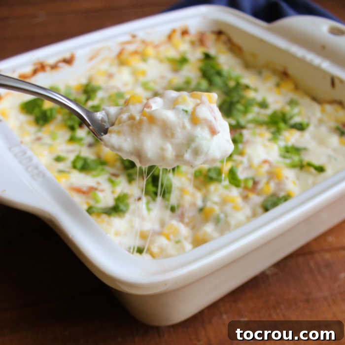 Ultimate Cheesy Corn Dip 3 A spoon pulling a generous serving of warm corn dip from a skillet, showcasing rich, cheesy strings and the creamy texture, inviting you to taste.