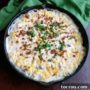 Ultimate Cheesy Corn Dip 7 A cast iron pan filled with creamy corn dip, generously topped with crispy bacon and fresh herbs, presented as the main recipe image.
