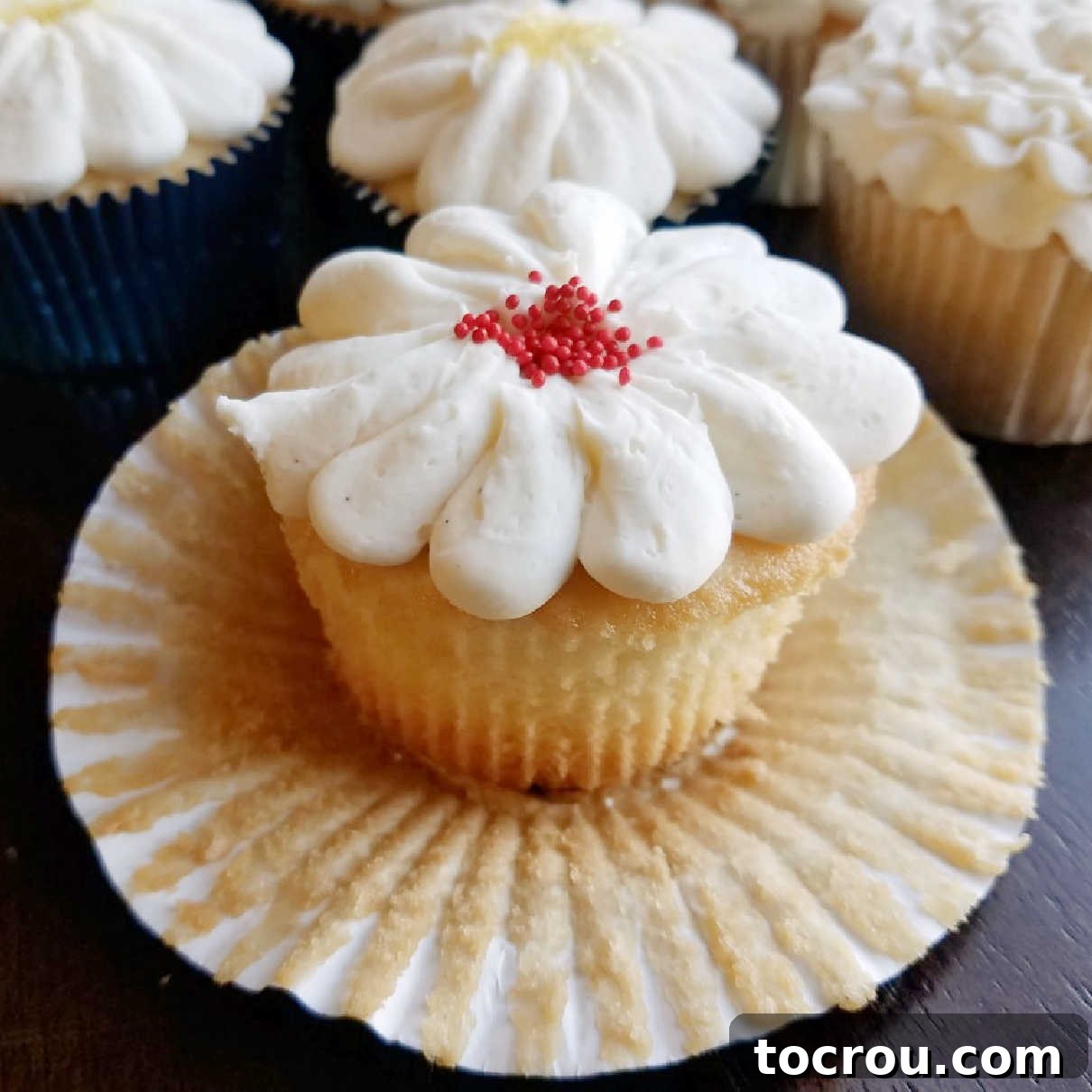 Fluffy white cupcakes are made perfect with a cake mix and a lot of add ins to make them special. They are the perfect texture, flavor and will quickly become your favorites as well! Close-up of a perfectly baked, fluffy white cupcake with its wrapper peeled down, revealing its pristine white crumb.