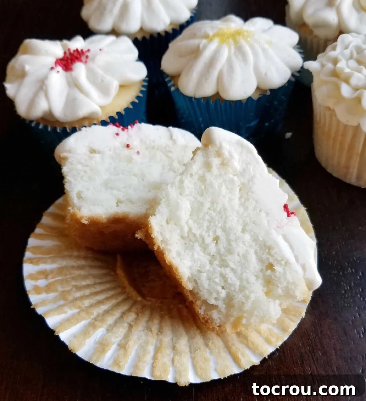 Fluffy white cupcakes are made perfect with a cake mix and a lot of add ins to make them special. They are the perfect texture, flavor and will quickly become your favorites as well! Semi-homemade white cupcake cut in half, showcasing its incredibly soft, fluffy, and pristine white interior crumb.