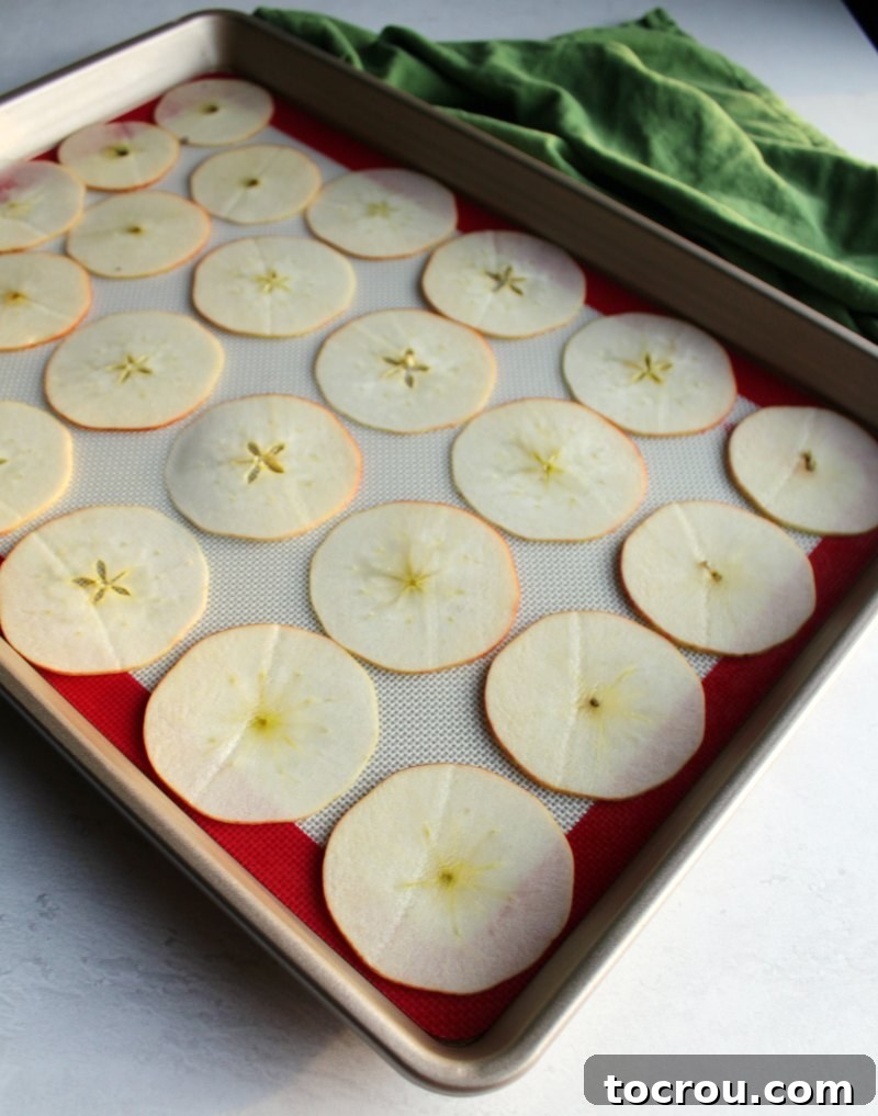 Wholesome Oven-Baked Apple Crisps 5 Apple slices laid out on baking sheet ready to go in oven an be made into apple chips.