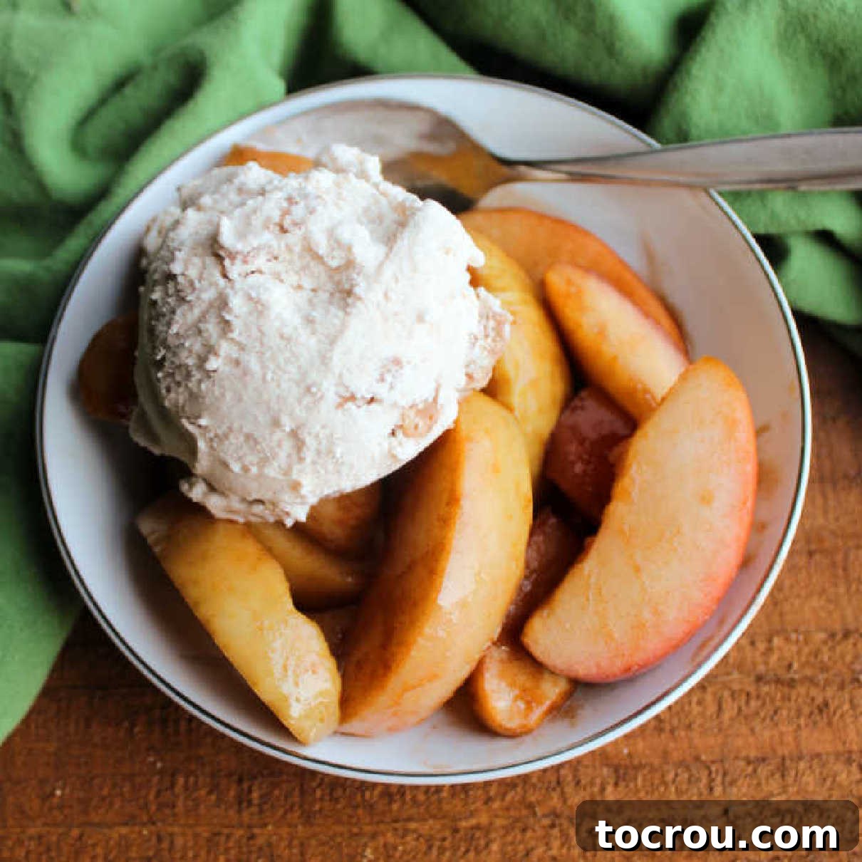 Warm Cinnamon Apple Delight 2 Small bowl of crockpot cinnamon apples served with a scoop of ice cream and a spoon.