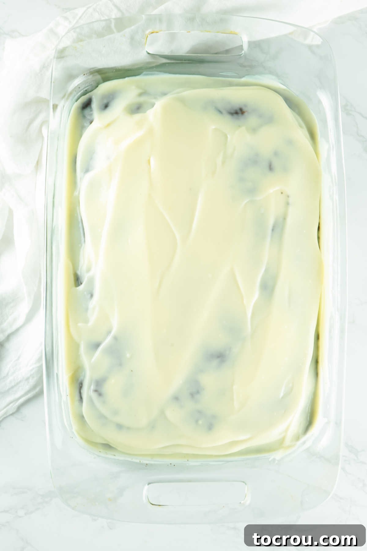 Hole-y Oreo Heaven 7 A warm Oreo chocolate poke cake generously covered with a thick, smooth layer of instant pudding mixture, ready to be chilled and absorb all the creamy goodness.