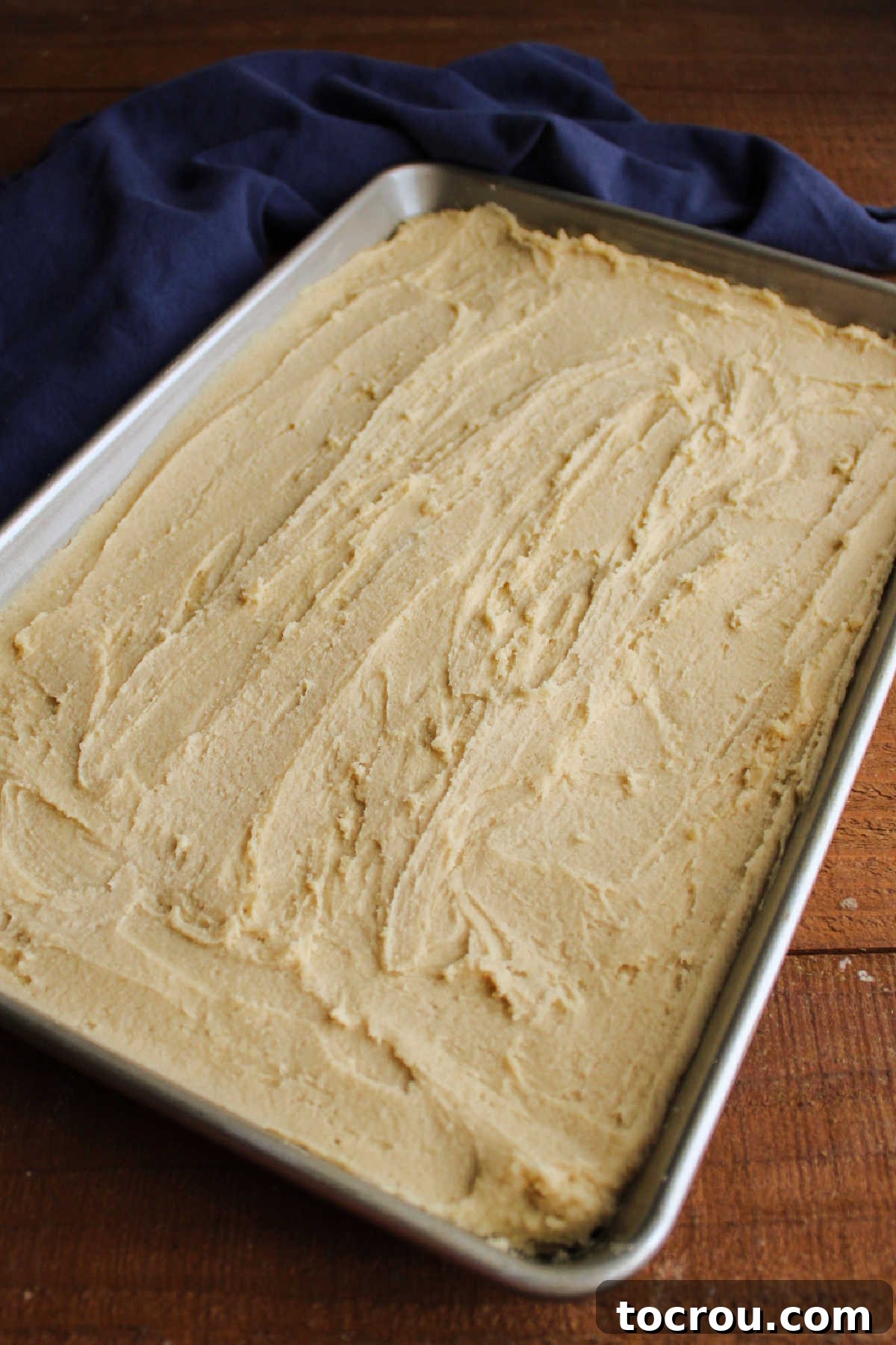 Smooth, unbaked toffee cookie dough spread evenly across a 10x15-inch baking pan, perfectly prepared for the oven.