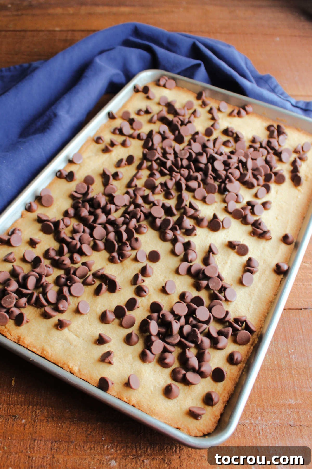 Warm, freshly baked toffee cookie bars, still in the pan, covered with a layer of chocolate chips waiting to melt.