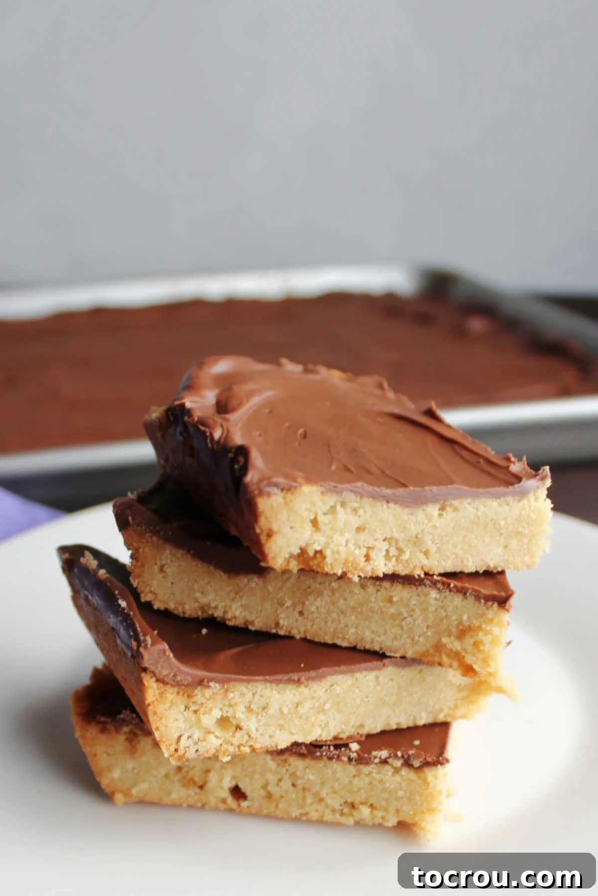 A close-up view of a neat stack of golden toffee cookie bars on a white plate, ready to be enjoyed.