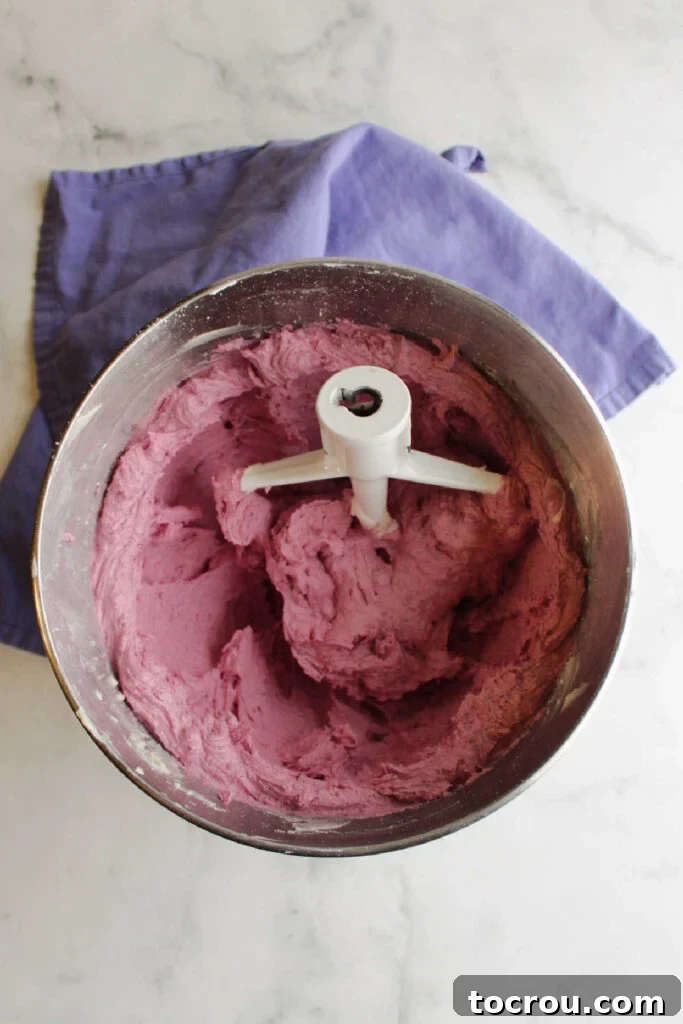 Mixer bowl filled with purple blueberry frosting.