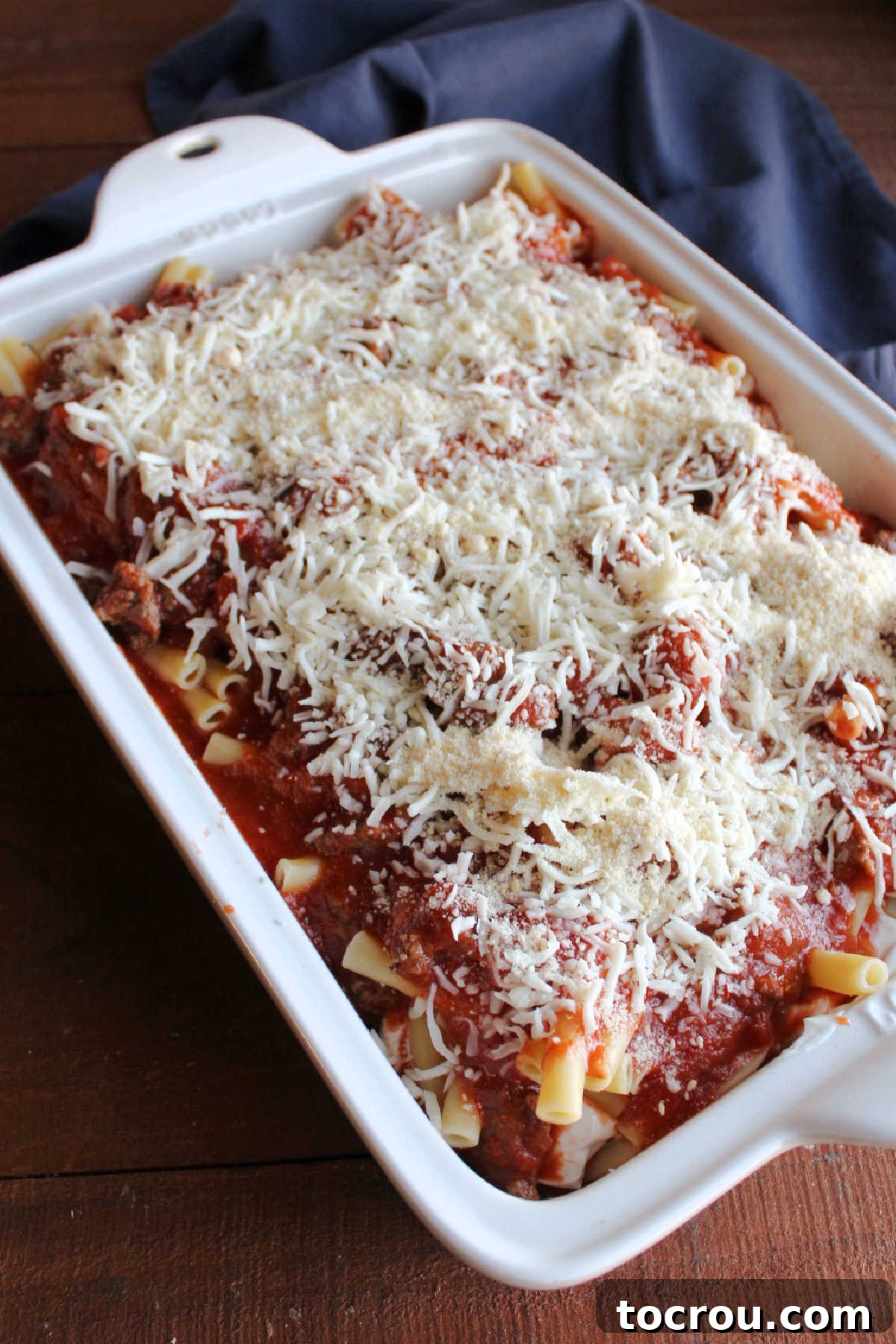 Mozzarella and Parmesan cheese generously sprinkled over the final layer of pasta and sauce, ready to be baked to a golden, bubbly finish.