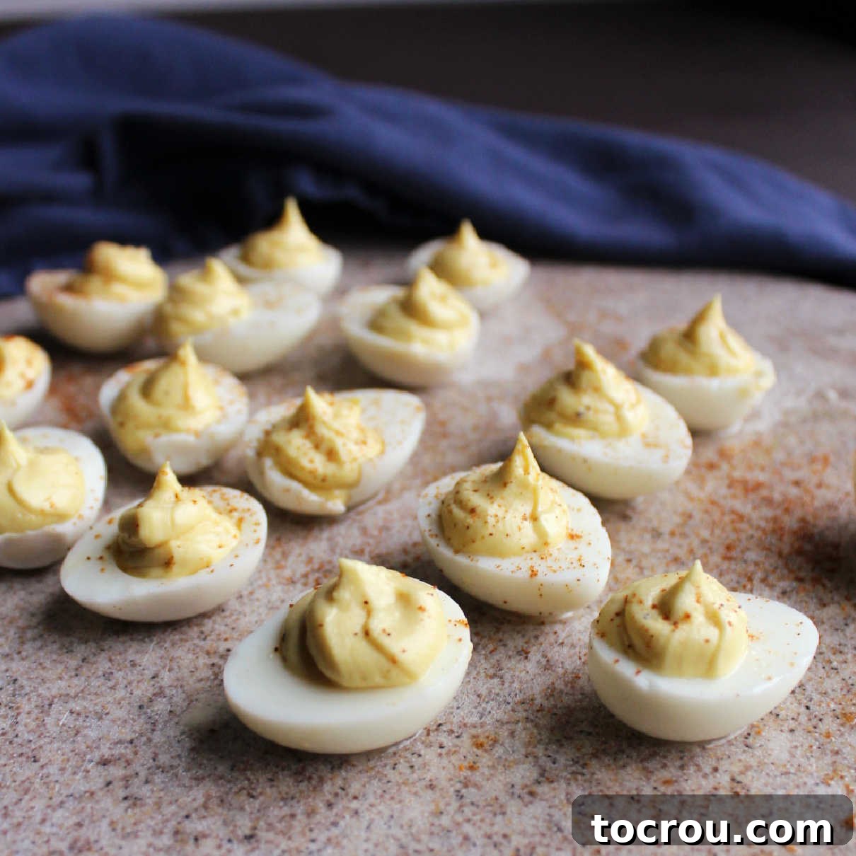 An inviting close-up of several finished deviled quail eggs, each filled with creamy yolk mixture and elegantly topped with a dusting of paprika.