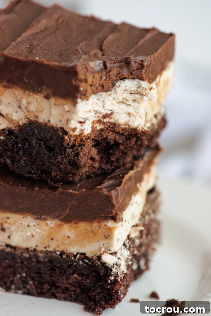 Close stack of coffee and cream brownies with layers of brownie, coffee frosting and ganache with bite missing from a corner.