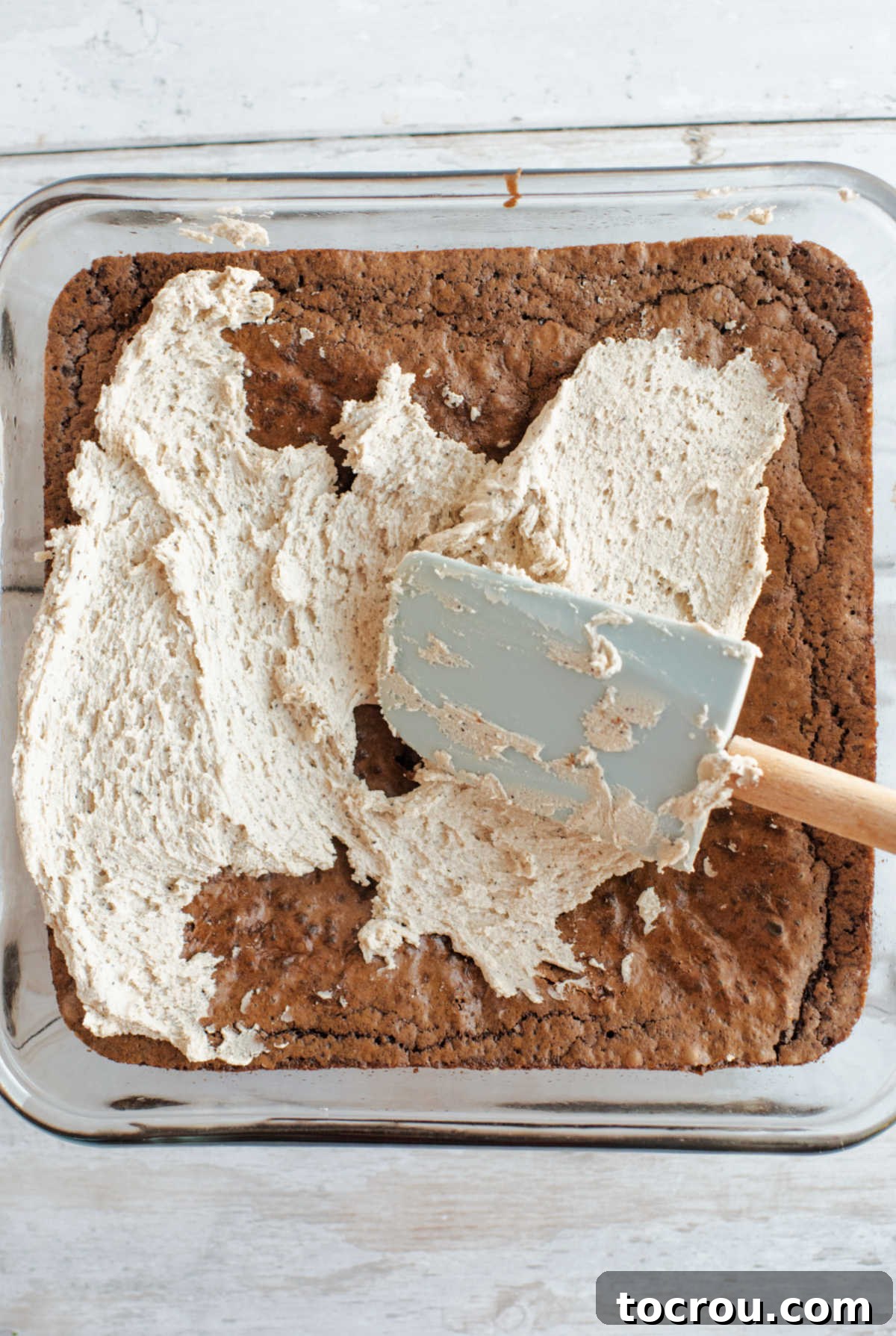 Spatula smoothing a little bit of coffee buttercream over cooled brownies.