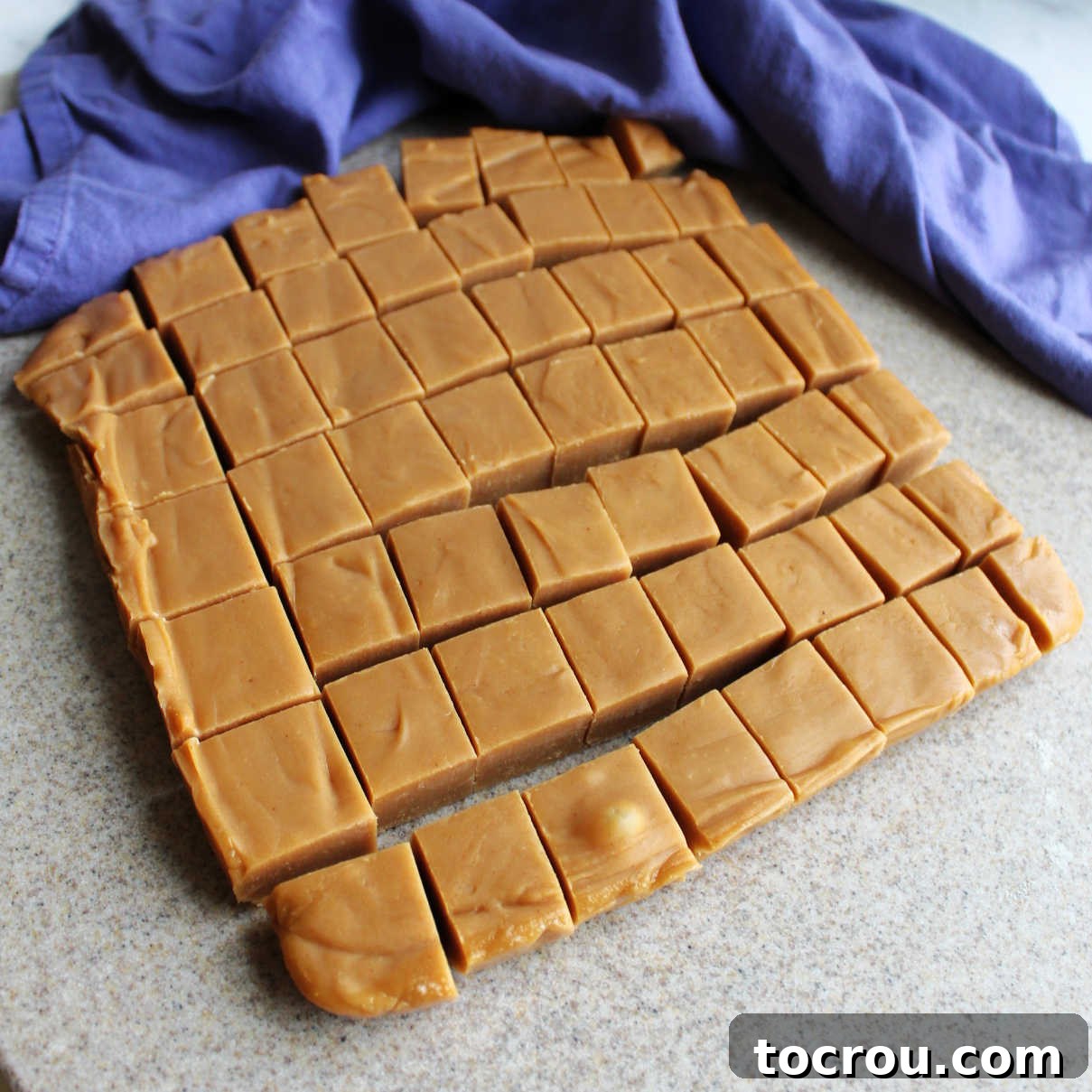 Precisely Cut Peanut Butter Fudge Set peanut butter fudge cut into perfect squares, ready for serving. The cuts are clean, showing the smooth, light brown interior.