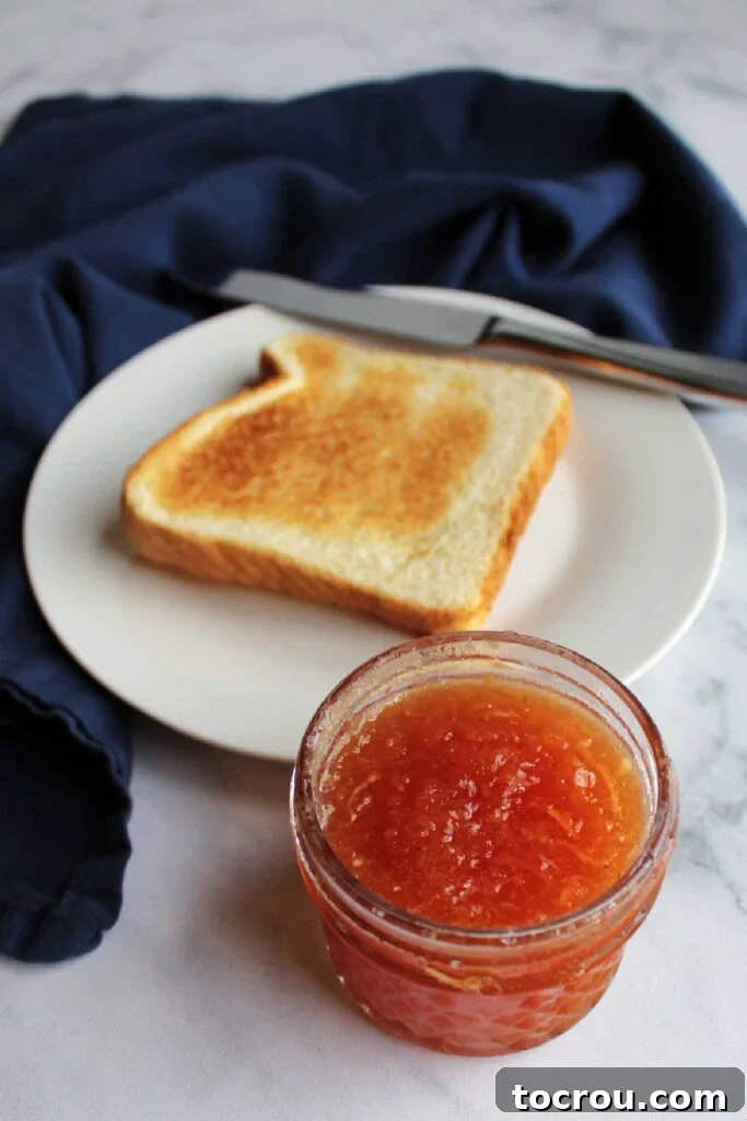 Homemade Strawberry Zucchini Jam Jar Jar of strawberry zucchini jam placed in front of a slice of toast, ready to be enjoyed.