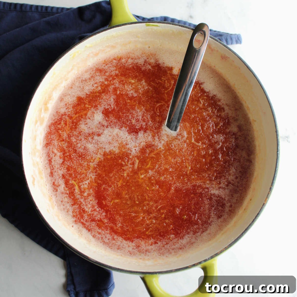 Freshly Cooked Zucchini Jam A saucepan filled with a vibrant reddish-peach colored jam, with a ladle poised to transfer it into jars.