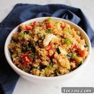 A close-up shot of a bowl filled with vibrant Mediterranean quinoa salad, showcasing the detailed textures of tomatoes, cucumbers, feta, and parsley, inviting to taste.
