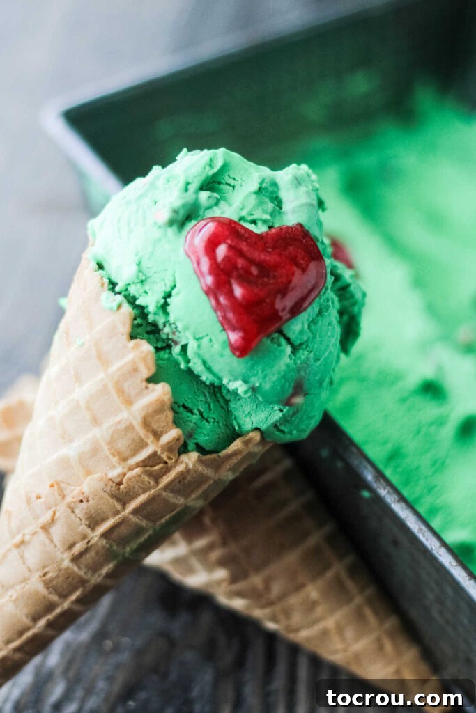 Mint Grinch Ice Cream Cone no churn mint ice cream in a cone with red icing heart.