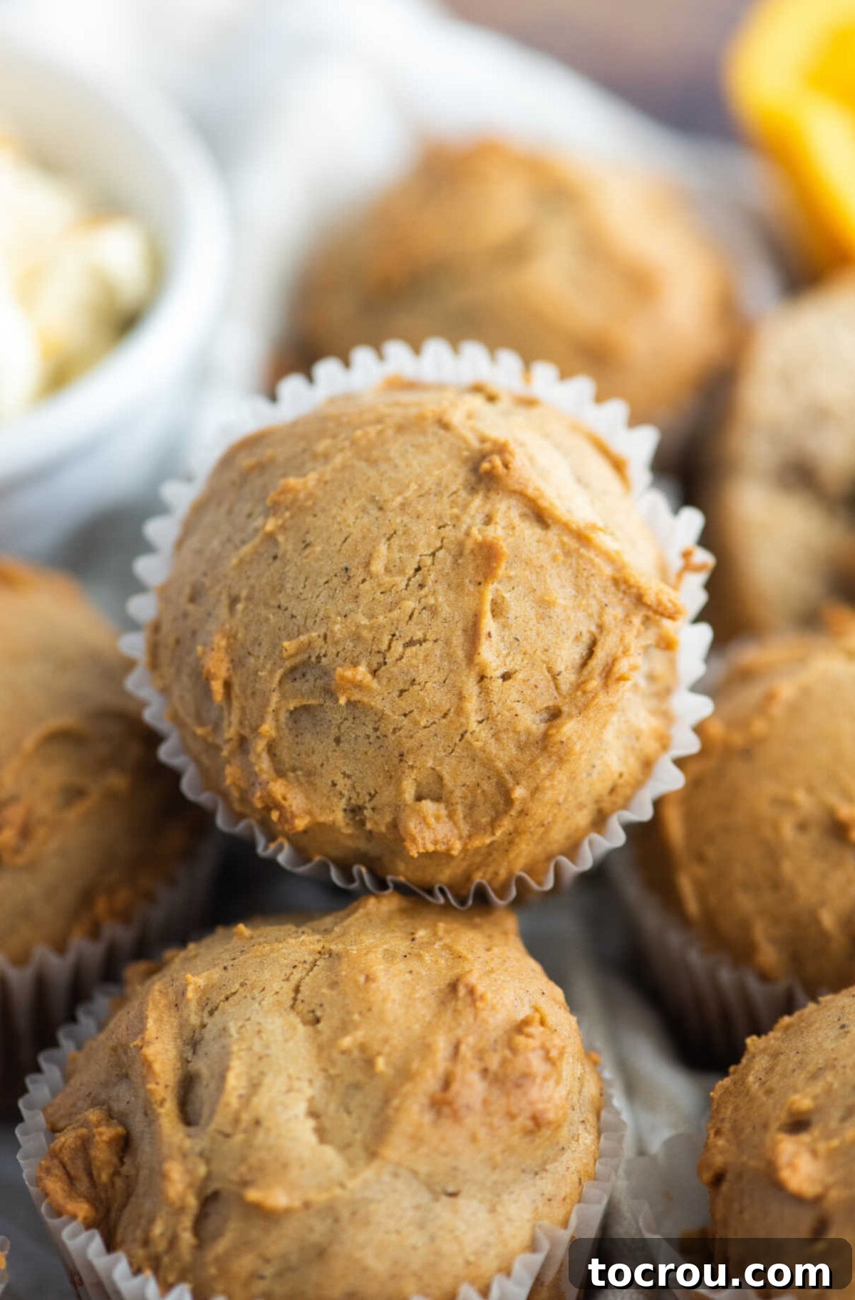 Freshly baked orange spice muffins with white paper wrappers, arranged on a cooling rack.