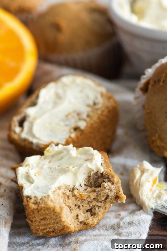 A bite taken out of a honey butter covered orange spice muffin half, showing its fluffy texture.
