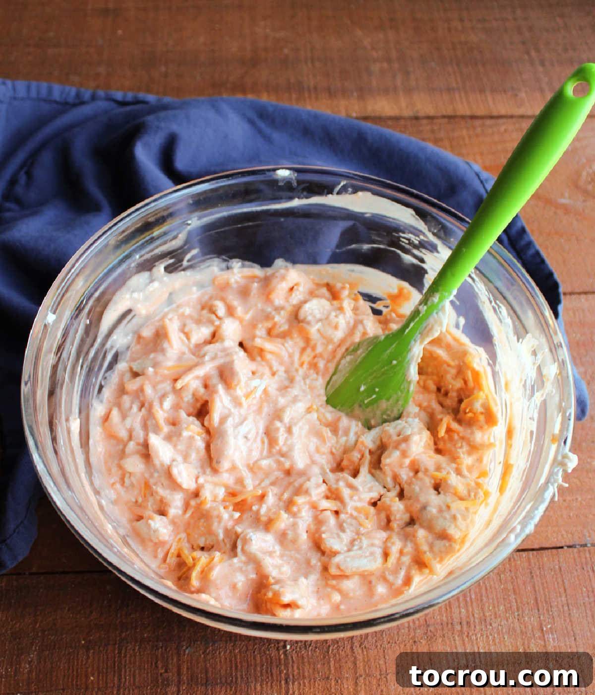 Ultimate Creamy Buffalo Chicken Dip 4 A close-up shot of a large mixing bowl filled with the creamy, orange-hued buffalo chicken dip mixture, showing the shredded chicken, melted cream cheese, and seasonings perfectly blended, promising rich flavor before baking.