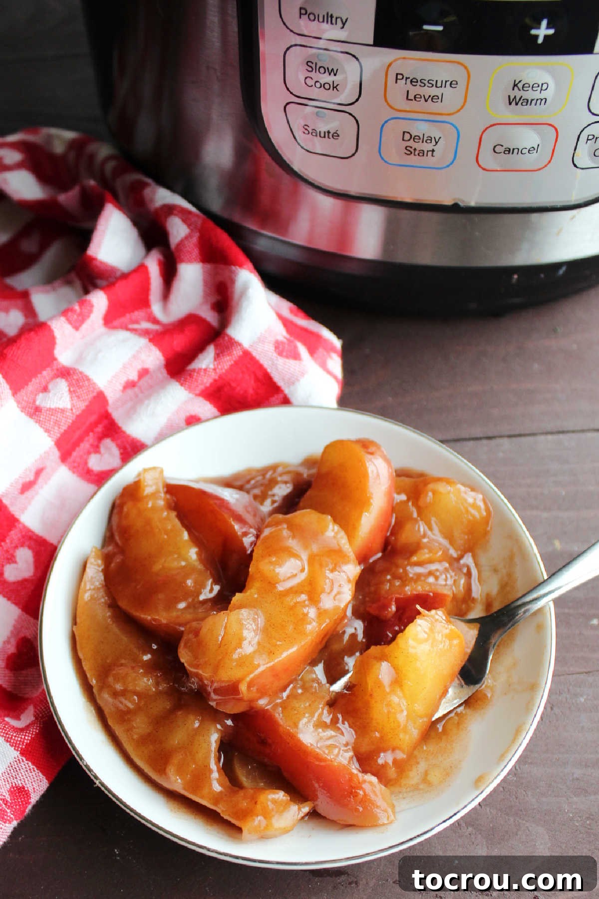 Spoon in a bowl of cinnamon fried apples with fork, ready to eat. 
