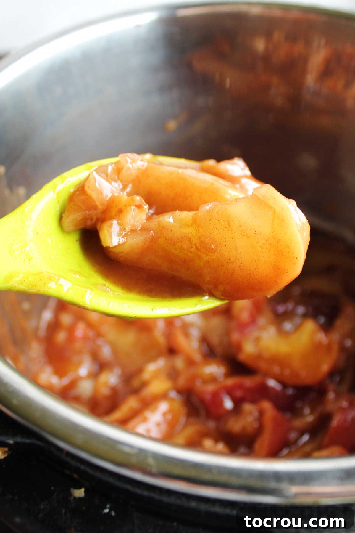 spoonful of warm cinnamon apples over instant pot, ready to serve.