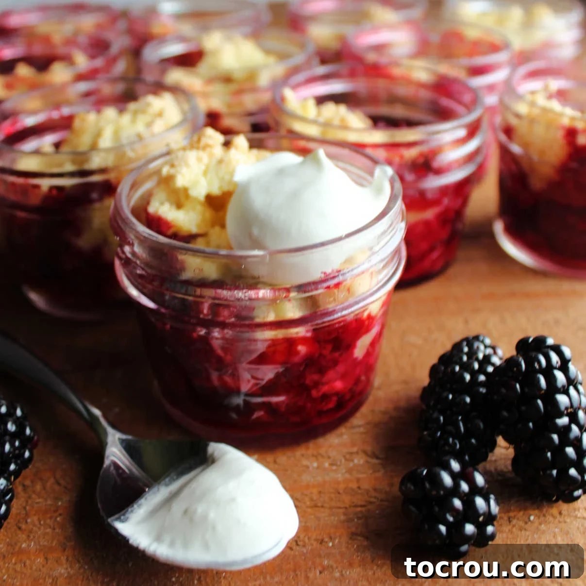Close look at jars of blackberry cobbler with whipped cream. 