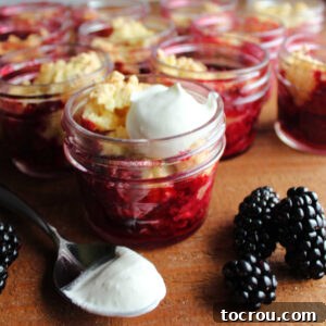 Close look at jars of blackberry cobbler with whipped cream.