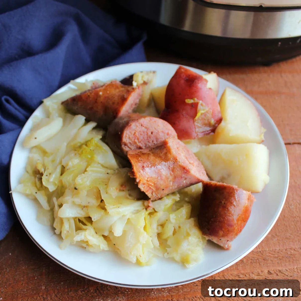 Plate filled with cooked sausage, potatoes and cabbage.