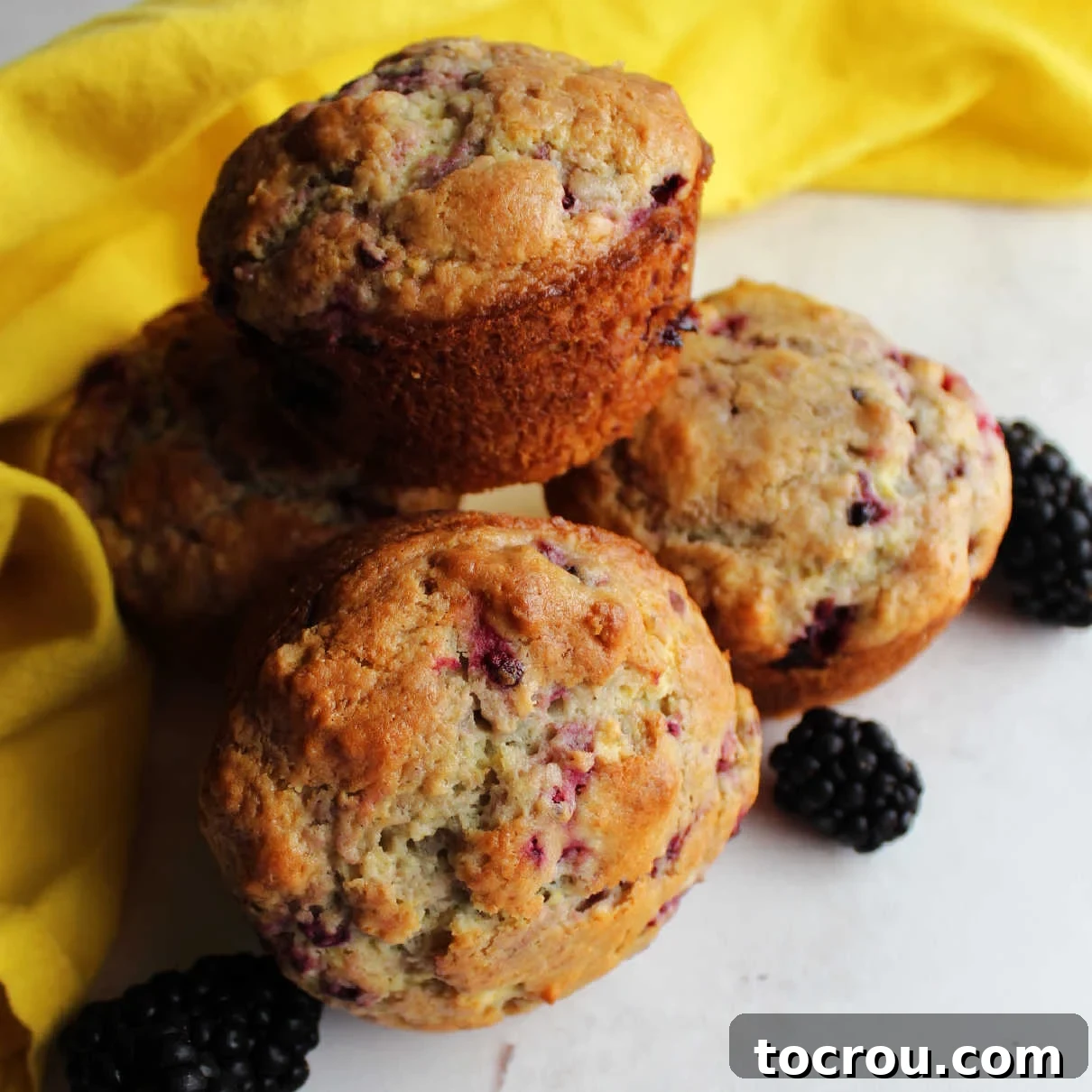 Close up of a stack of golden blackberry sour cream muffins, ready to be enjoyed.