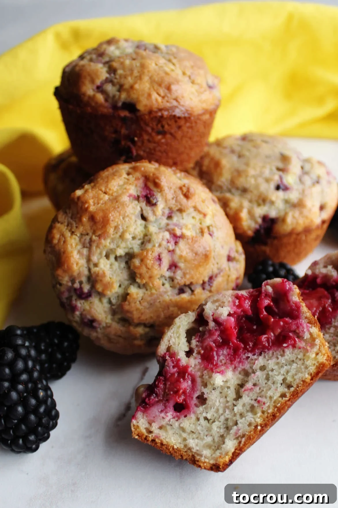 A close-up view of the inside of a blackberry sour cream muffin, showing large purple berry splotches.